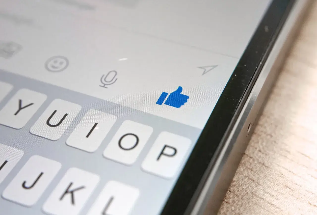 Kciuk w górę na ekranie telefonu, pokazujący, jak działa aktywność na Messengerze. Klawiatura i ikony czatu.