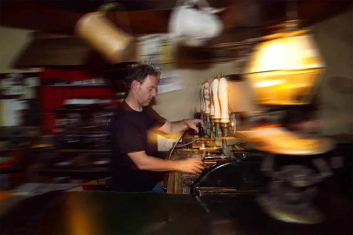 Barista serve birra a un beer fest, con spillatori e bicchieri in movimento.