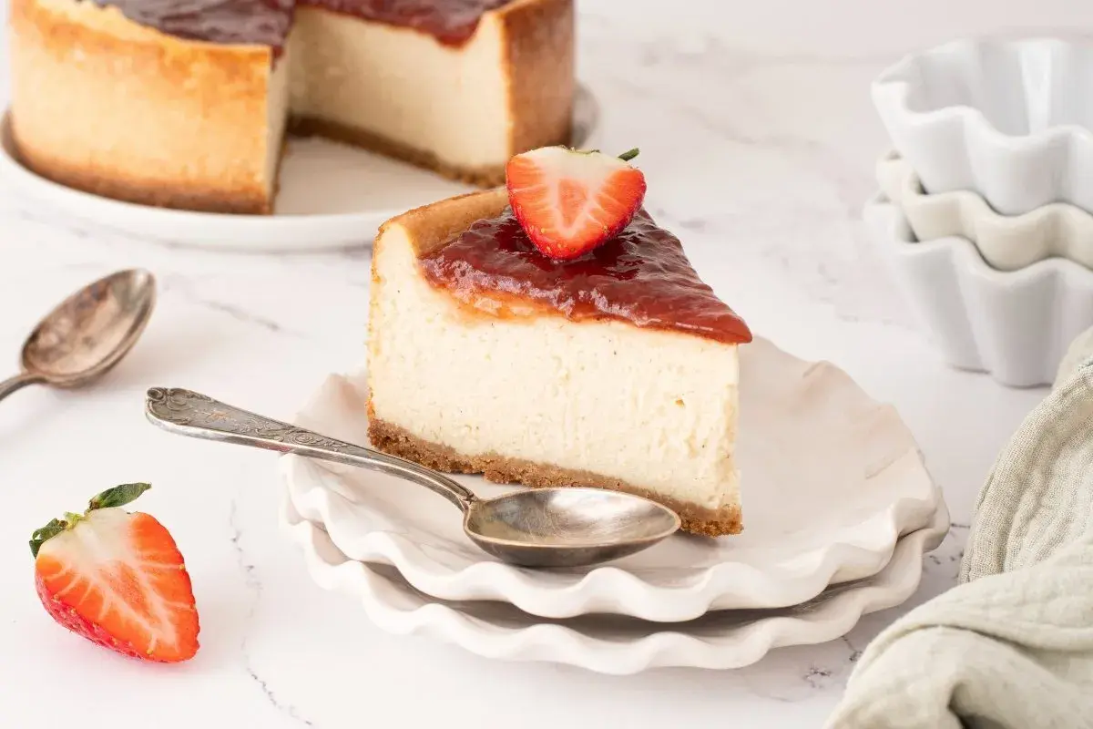 Deliciosa tarta de queso vegana con cobertura de fresa y una fresa fresca encima.