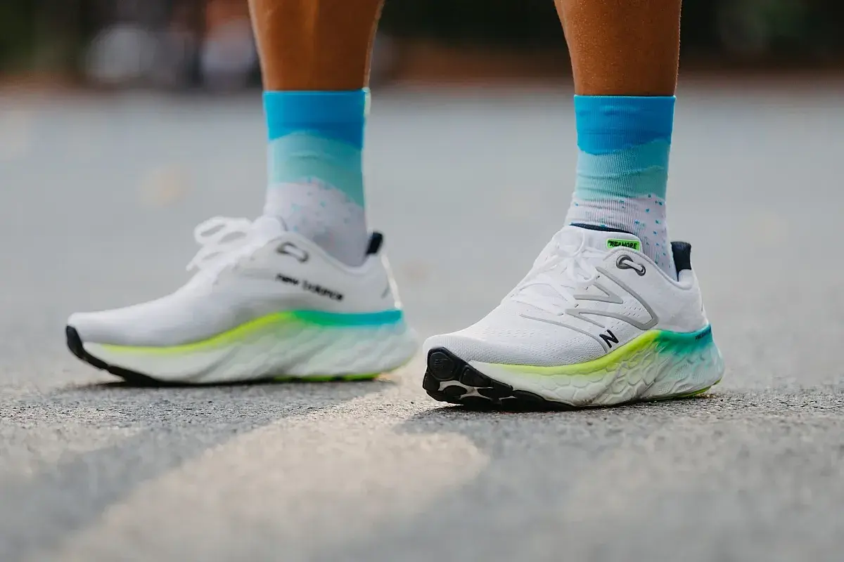Białe buty do biegania New Balance z kolorową podeszwą i skarpetki w chmurki. Dowiedz się, jak dobrać buty do biegania.