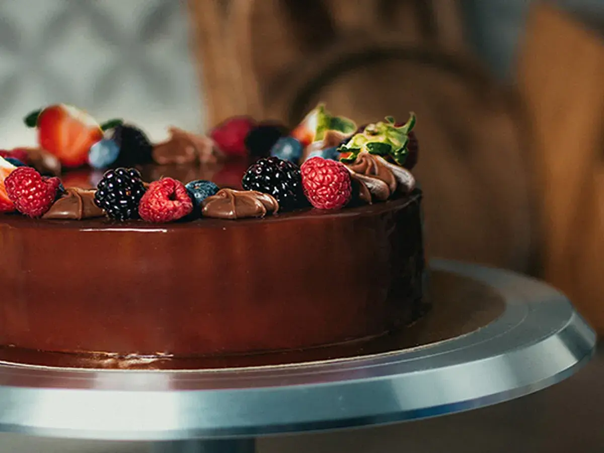 Una deliziosa torta di compleanno con frutta e cioccolato, decorata con fragole, lamponi, mirtilli e more.