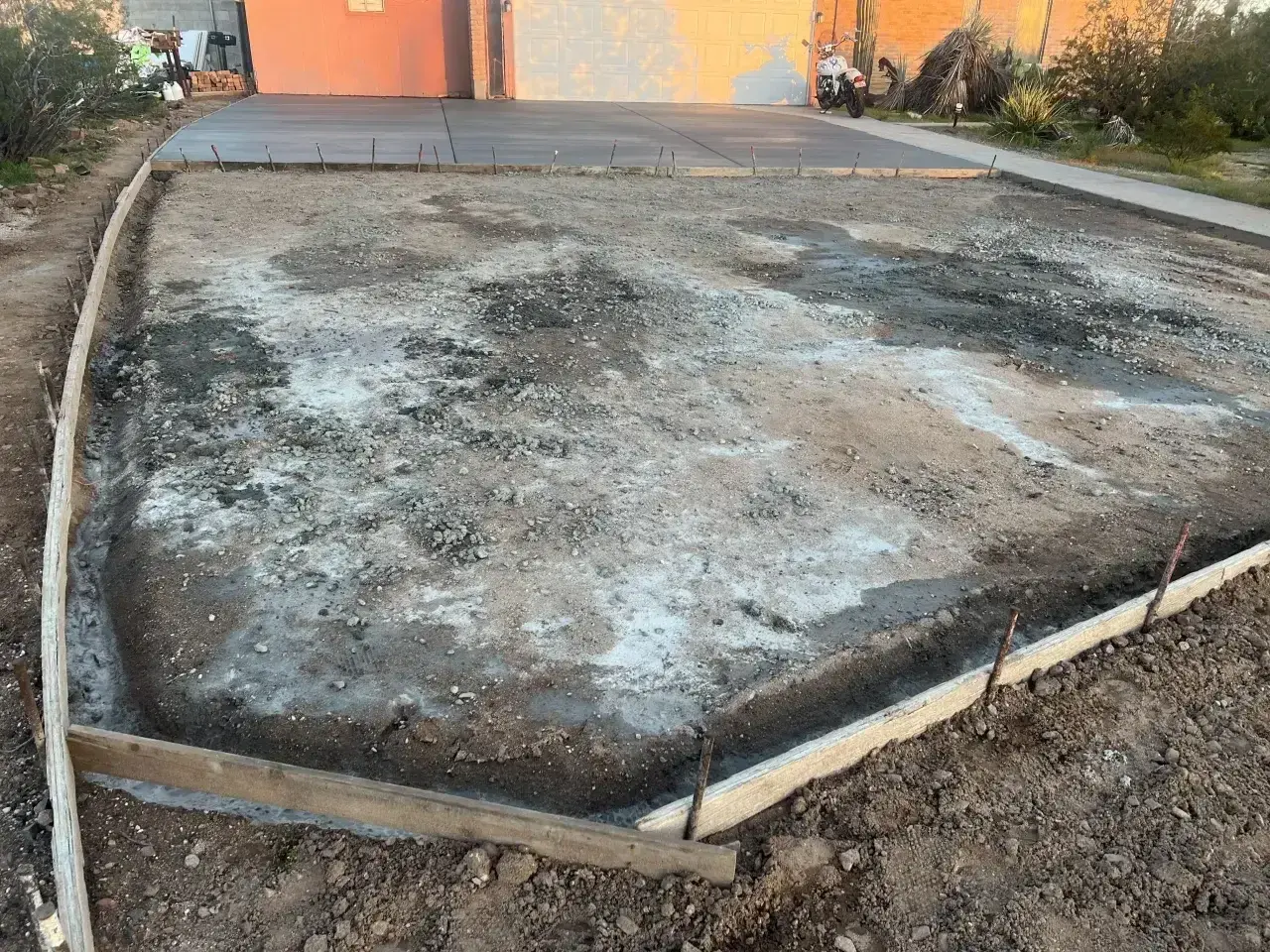 Plac budowy podjazdu z kamienia. Widać szalunki i przygotowany teren pod wylanie betonu.