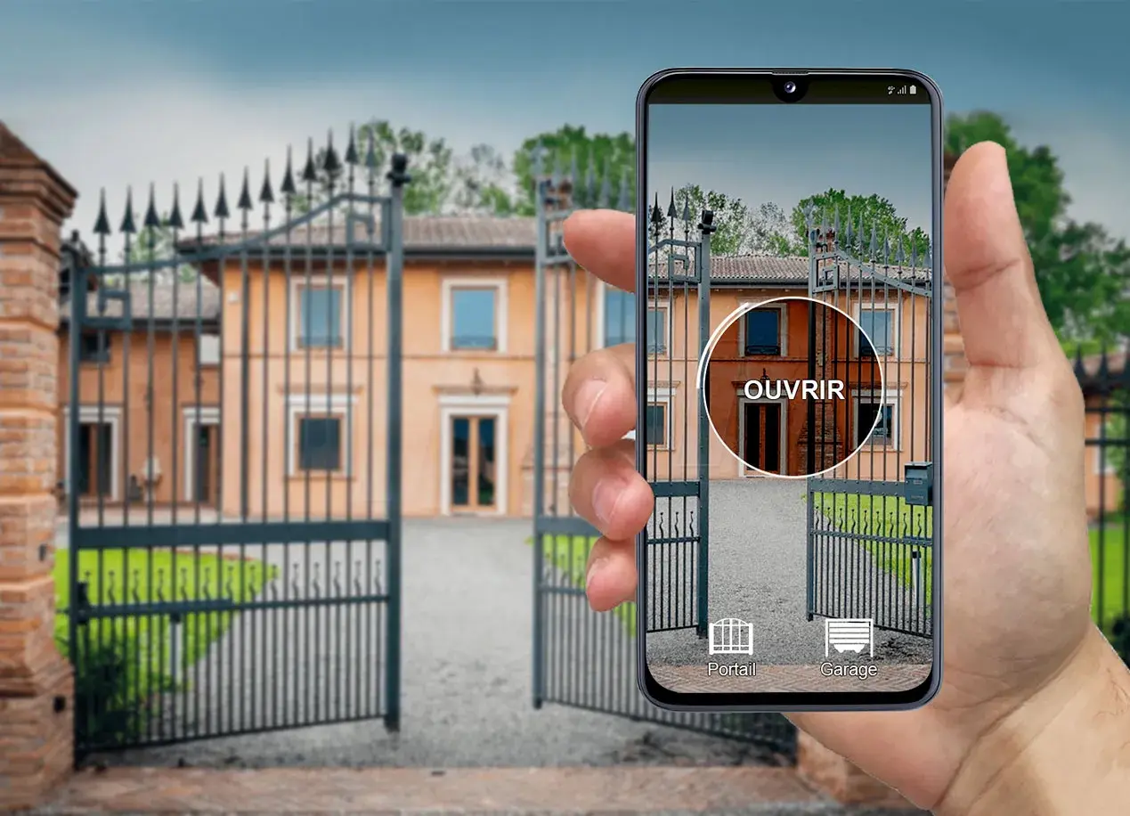 Une main tient un iPhone affichant une application de télécommande universelle pour ouvrir le portail d'une villa.