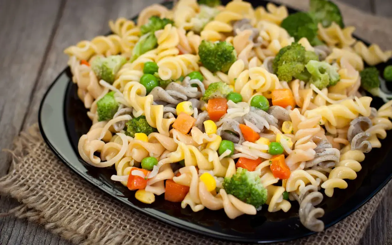 Deliciosa ensalada de pasta vegana con brócoli, guisantes, zanahoria y maíz. Un plato colorido y saludable.