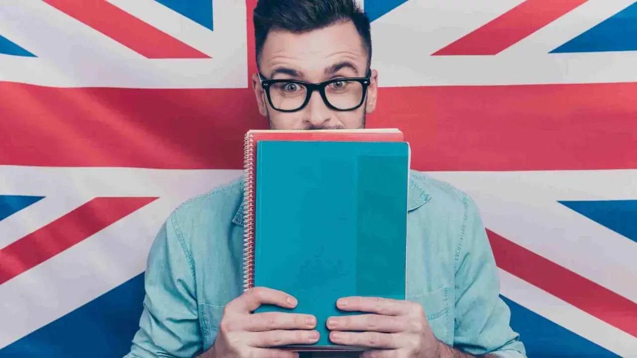 Studente con quaderni davanti al volto, sullo sfondo la Union Jack. Chissà se impara come si dice "venerdì" in inglese.