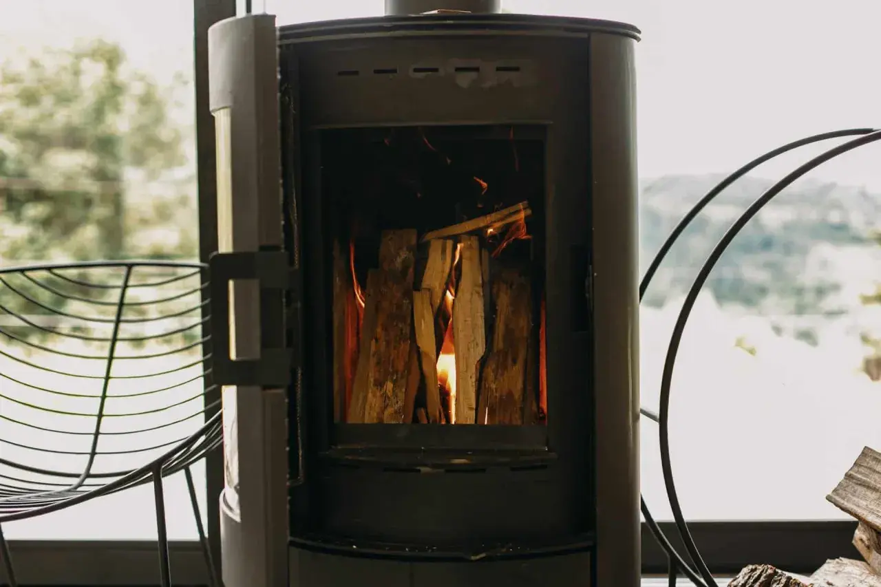 Poêle à bois allumé, avec une prise d'air poele à bois obligatoire pour une combustion optimale. Le feu crépite joyeusement.