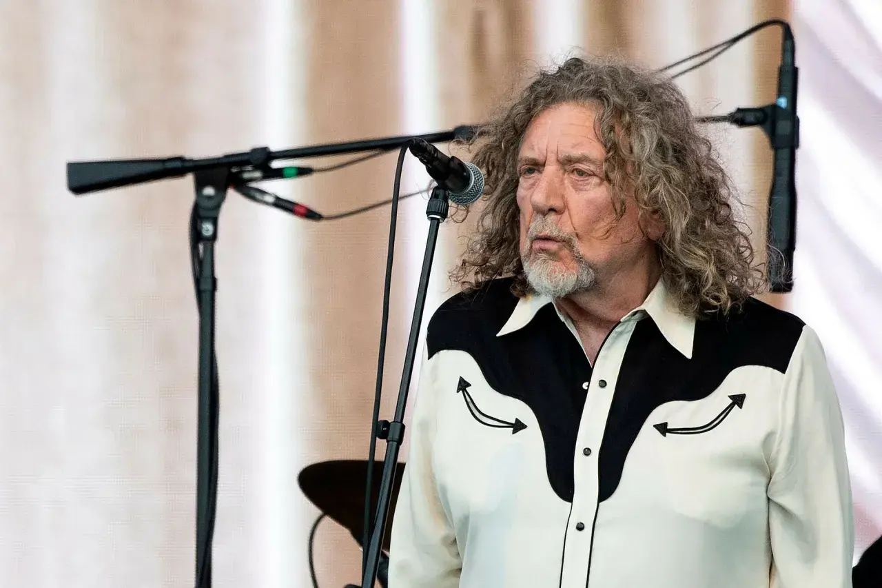 Robert Plant, jeden z legendarnych członków Led Zeppelin, na scenie z charakterystyczną fryzurą i koszulą.