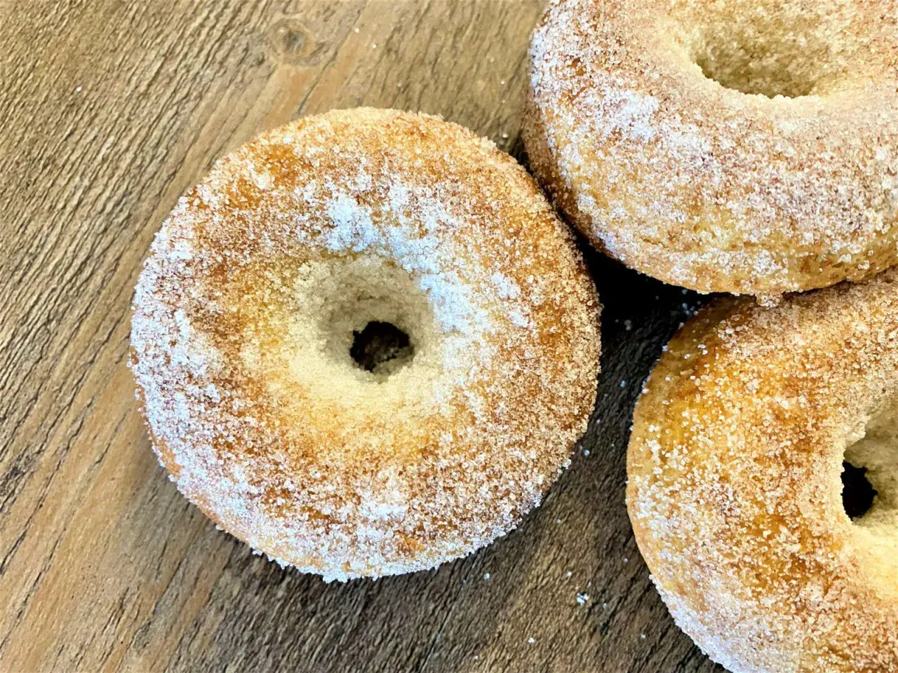 Trois donuts dorés, saupoudrés de sucre, prêts à être dégustés. Une recette donuts simple et gourmande.