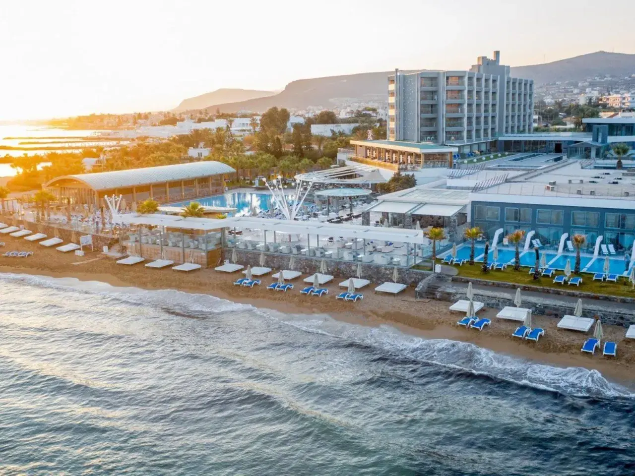 Das Arina Beach Resort erstreckt sich entlang eines Sandstrandes mit Pools, Liegen und einem Restaurant.