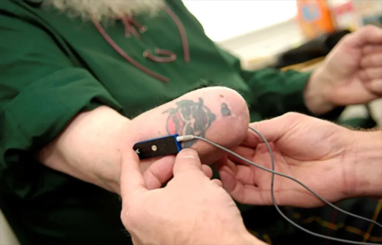 Un uomo con un tatuaggio sulla parte finale dell'avambraccio, forse a seguito di un'amputazione mano, tiene un dispositivo medico.