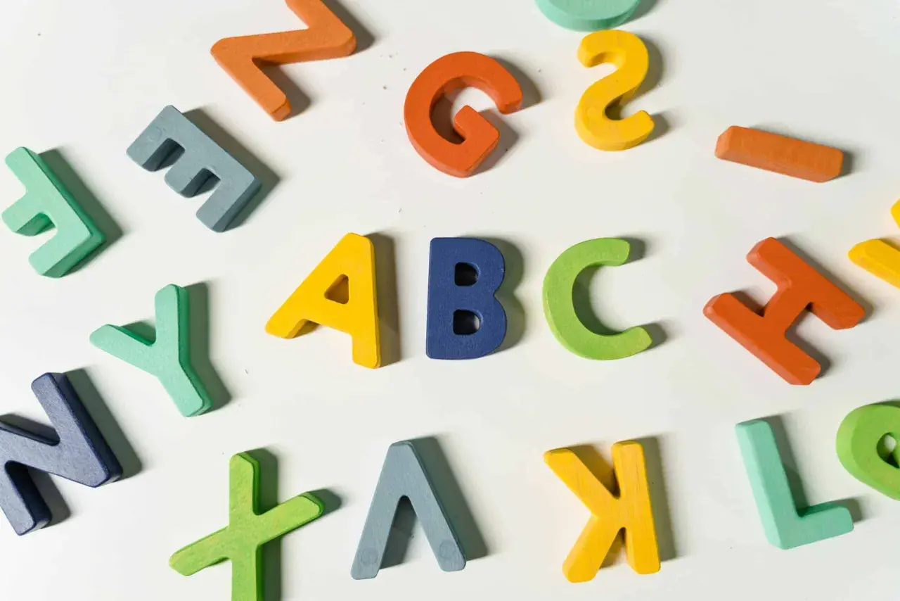 Kolorowe, drewniane litery układają się w napis "ABC", idealne do nauki angielskiego na poziomie a1.