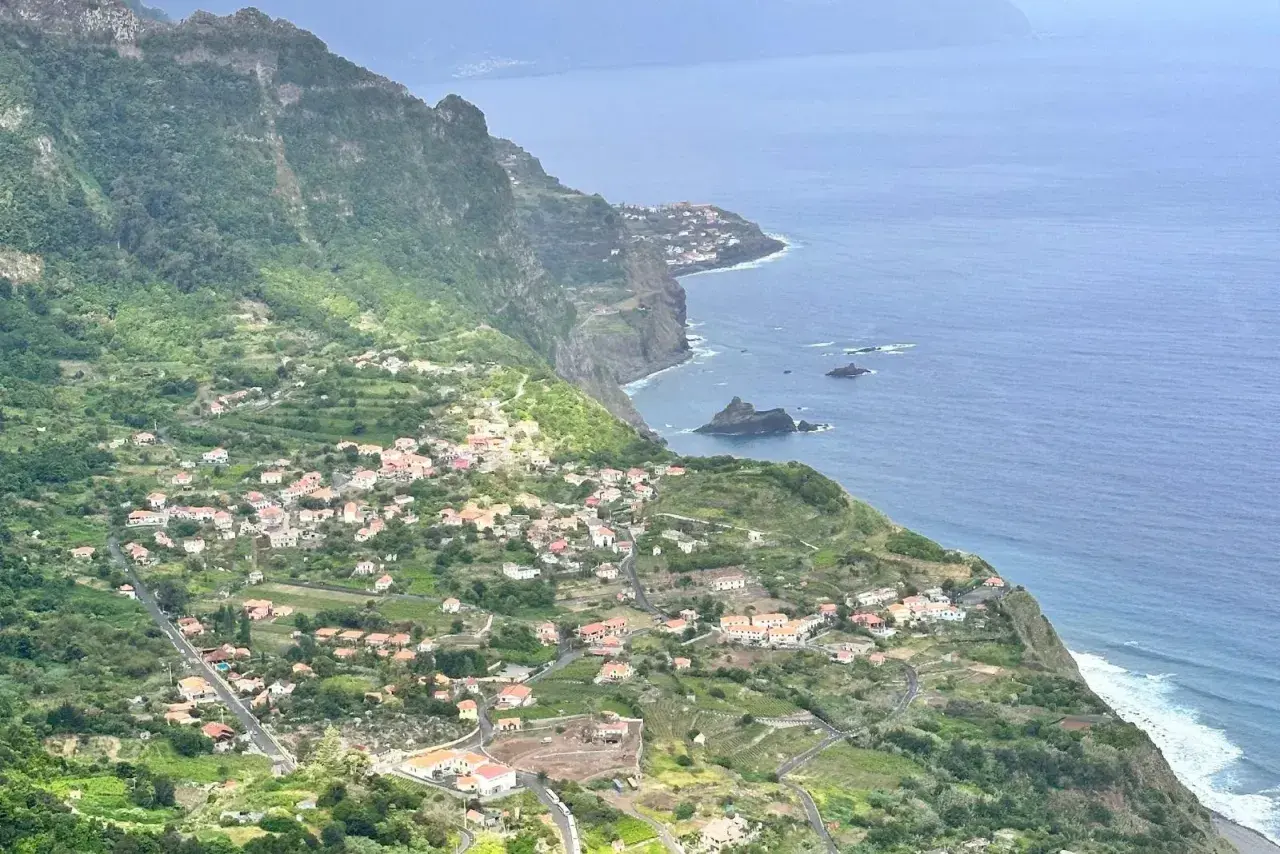 Grüne Hänge mit kleinen Häusern, die sich an die Küste schmiegen. Ein malerischer Anblick, der zu den Madeira Geheimtipps gehört.