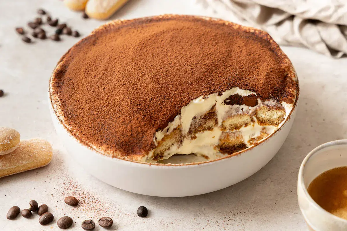 Un invitante tiramisù, una soffice mousse al cioccolato cosparsa di cacao, con savoiardi inzuppati e crema.