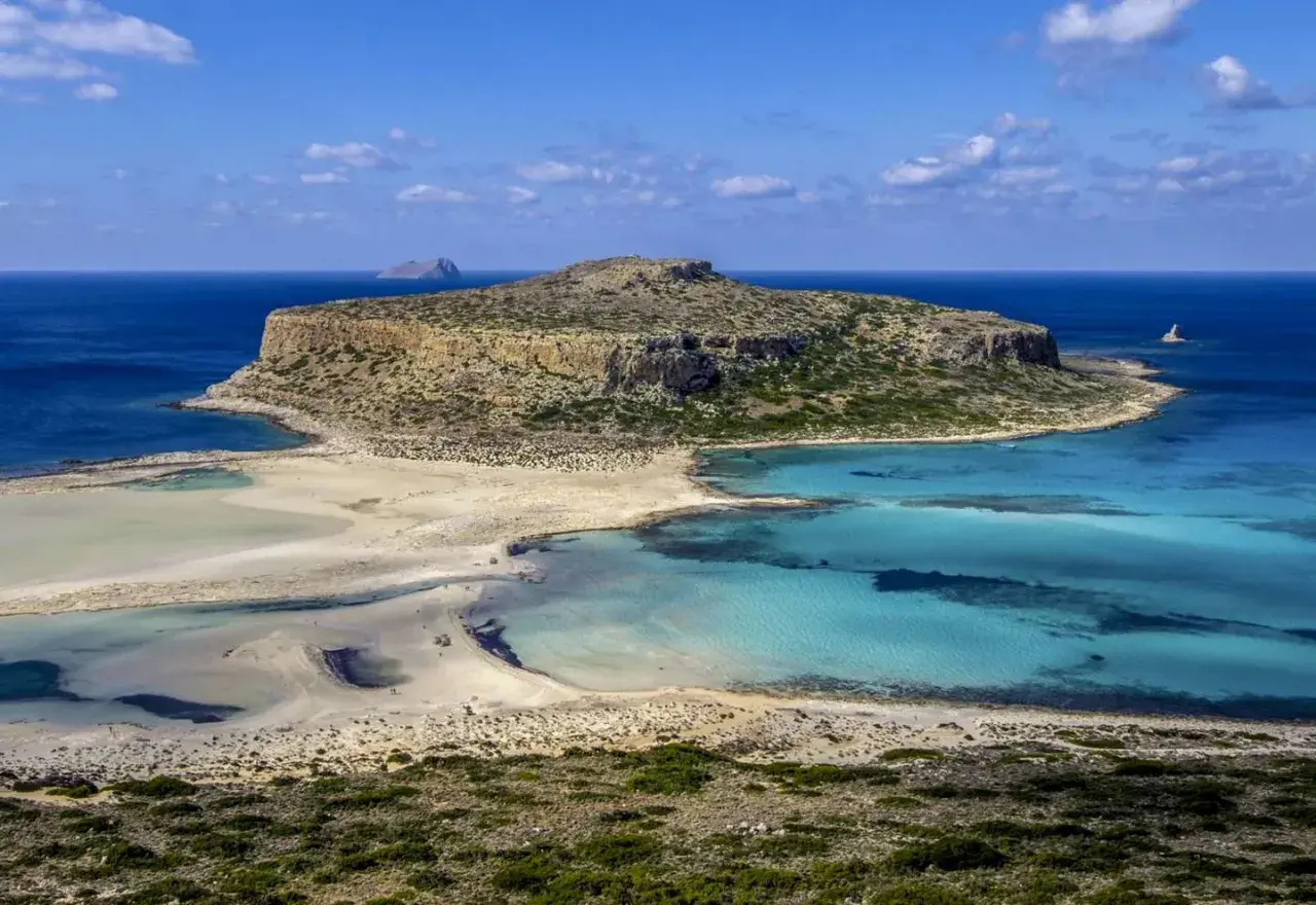 Malownicza zatoka z turkusową wodą i piaszczystą plażą, otoczona skalistymi klifami. To raj dla miłośników przyrody, ukazujący walory przyrodnicze Grecji.