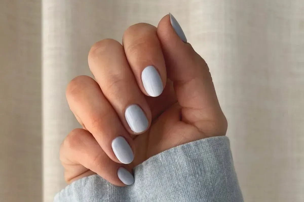 Dłoń z paznokciami w delikatnym baby blue kolorze.