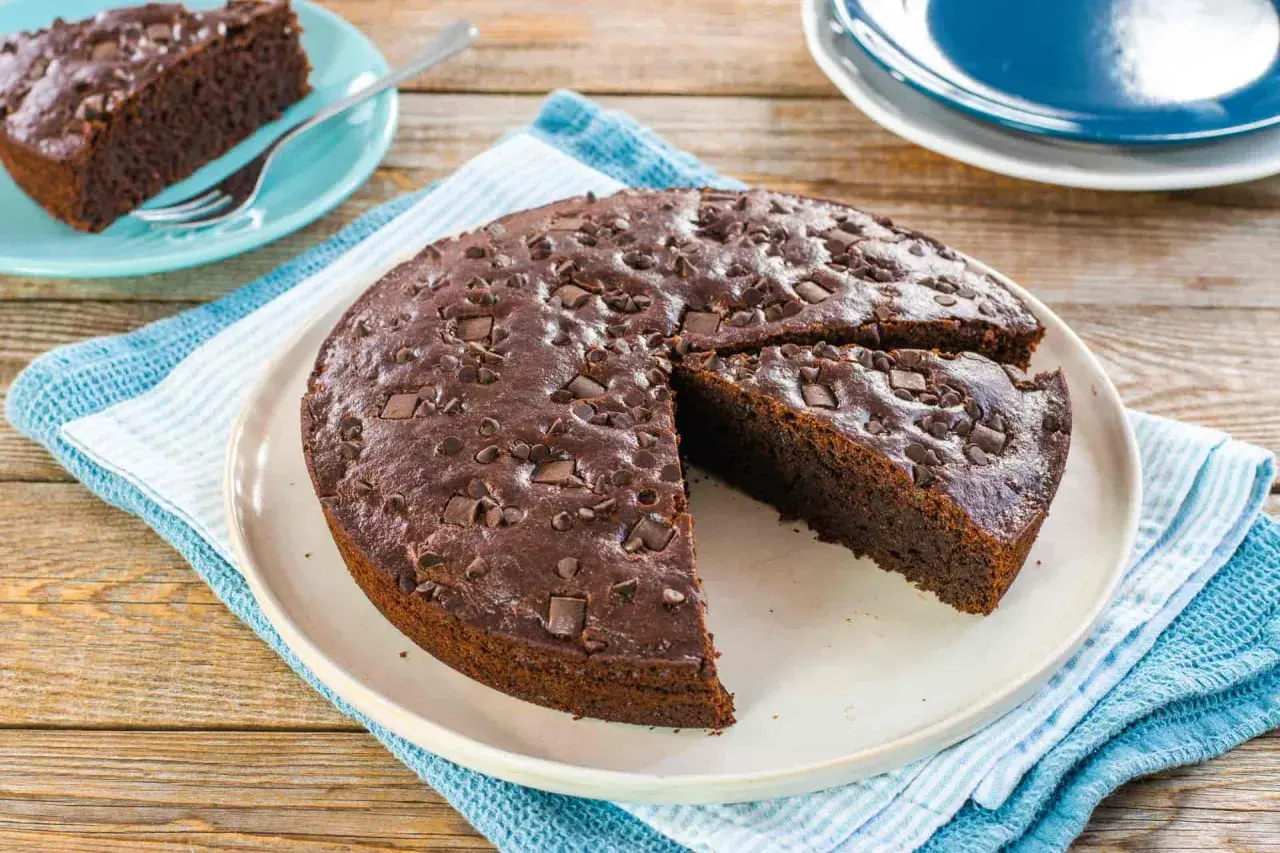 Deliziosa torta vegana al cioccolato, cosparsa di gocce e pezzi di cioccolato fondente, pronta per essere gustata.