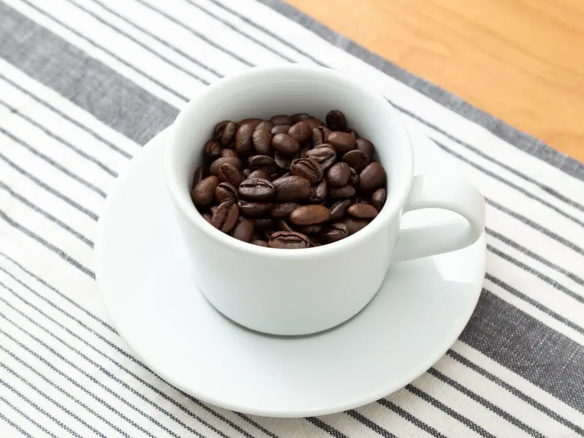 Eine Tasse gefüllt mit gerösteten Kaffeebohnen. Die Frage: filterkaffee wieviel gramm pro liter?
