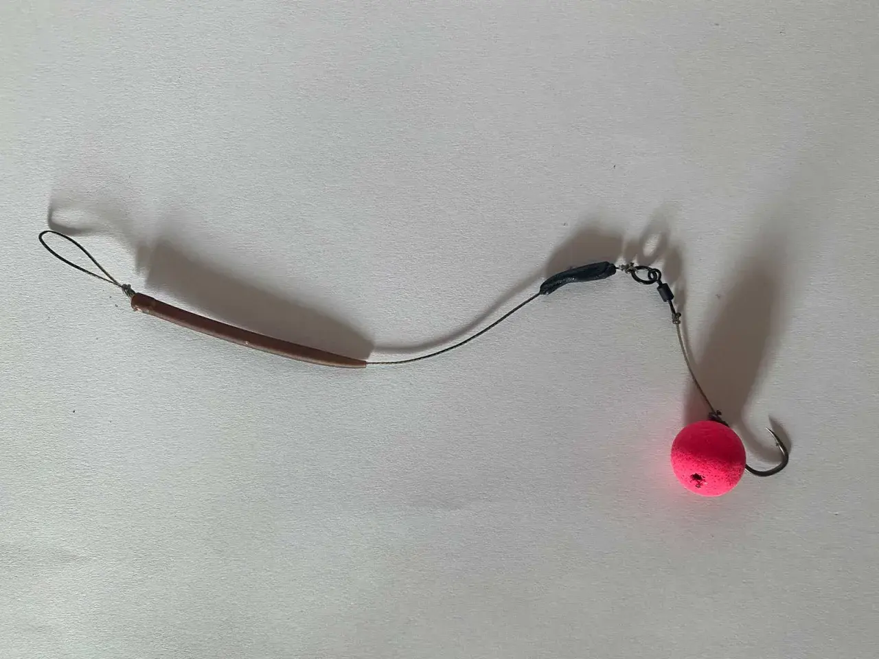 Ein **hinged stiff rig** mit einem pinken Pop-up Boilie und einem Haken.