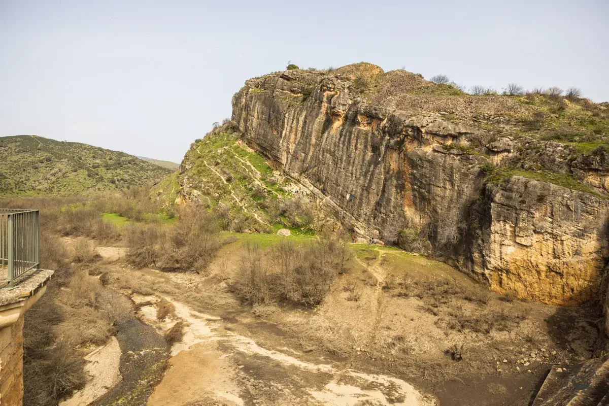 Escalada en la **ruta cañones del rio lozoya**. Un paisaje rocoso con un río seco y vegetación escasa.