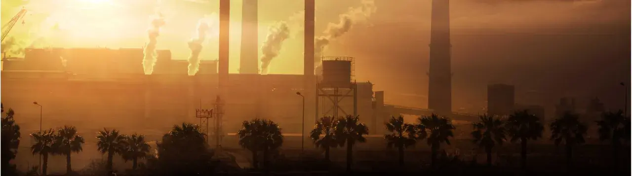 Paisaje industrial con chimeneas humeantes al atardecer. Ojalá se pudiera aplicar **limpieza con ozono** para purificar el aire.