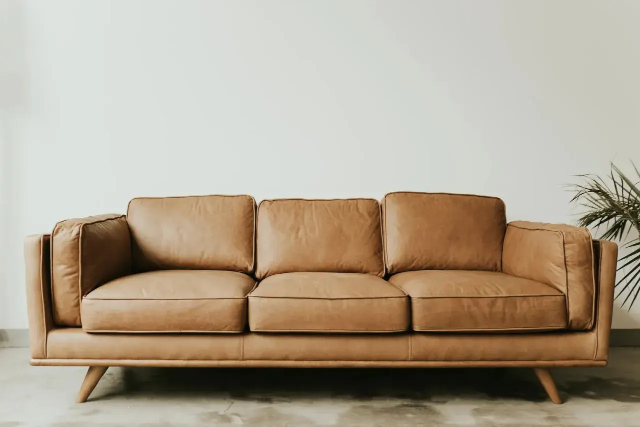 Canapé trois places en cuir aniline, couleur caramel, sur pieds en bois. Un fauteuil confortable pour votre salon.