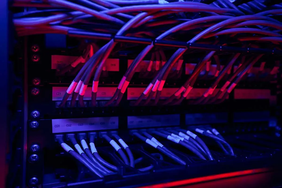 Red y azul iluminan un rack de servidores con un intrincado **cableado horizontal**.