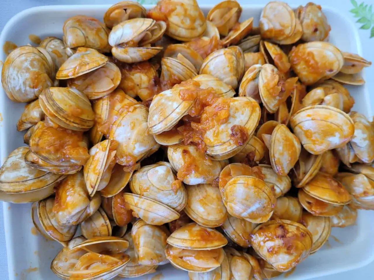 Un plato lleno de percebe gallego cocinado en una salsa anaranjada.