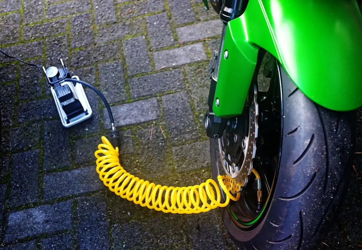 Compresor portátil conectado a la rueda de una moto para hinchar neumáticos con nitrógeno.