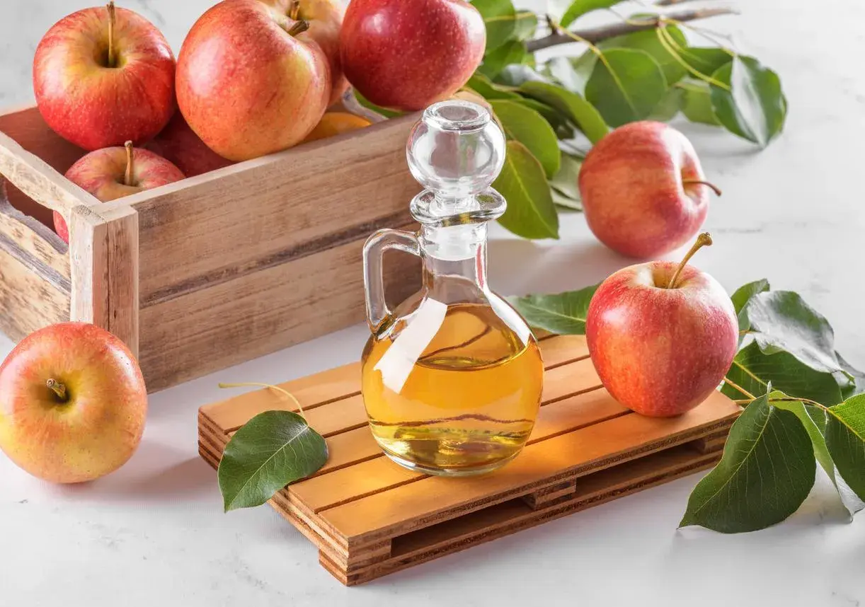 Bouteille de vinaigre de cidre et pommes fraîches, évoquant les bienfaits naturels pour la prostate.