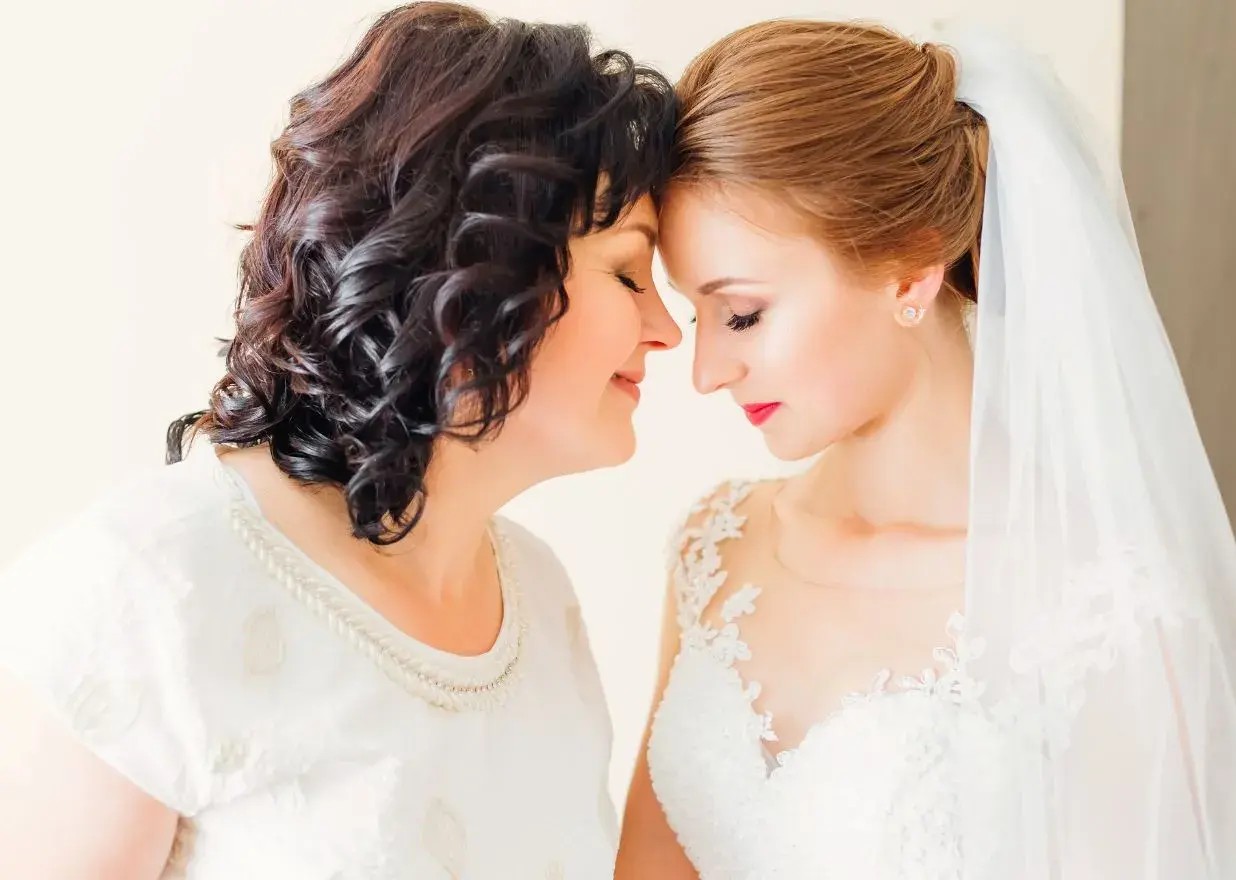 Mama i córka, obie elegancko na ślub córki, dzielą wzruszającą chwilę.