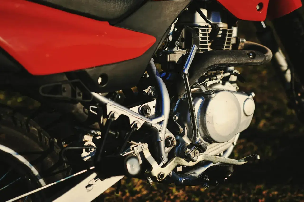 Silnik motocykla z czerwonym siedzeniem. Zastanawiasz się, świece irydowe co ile wymiana?