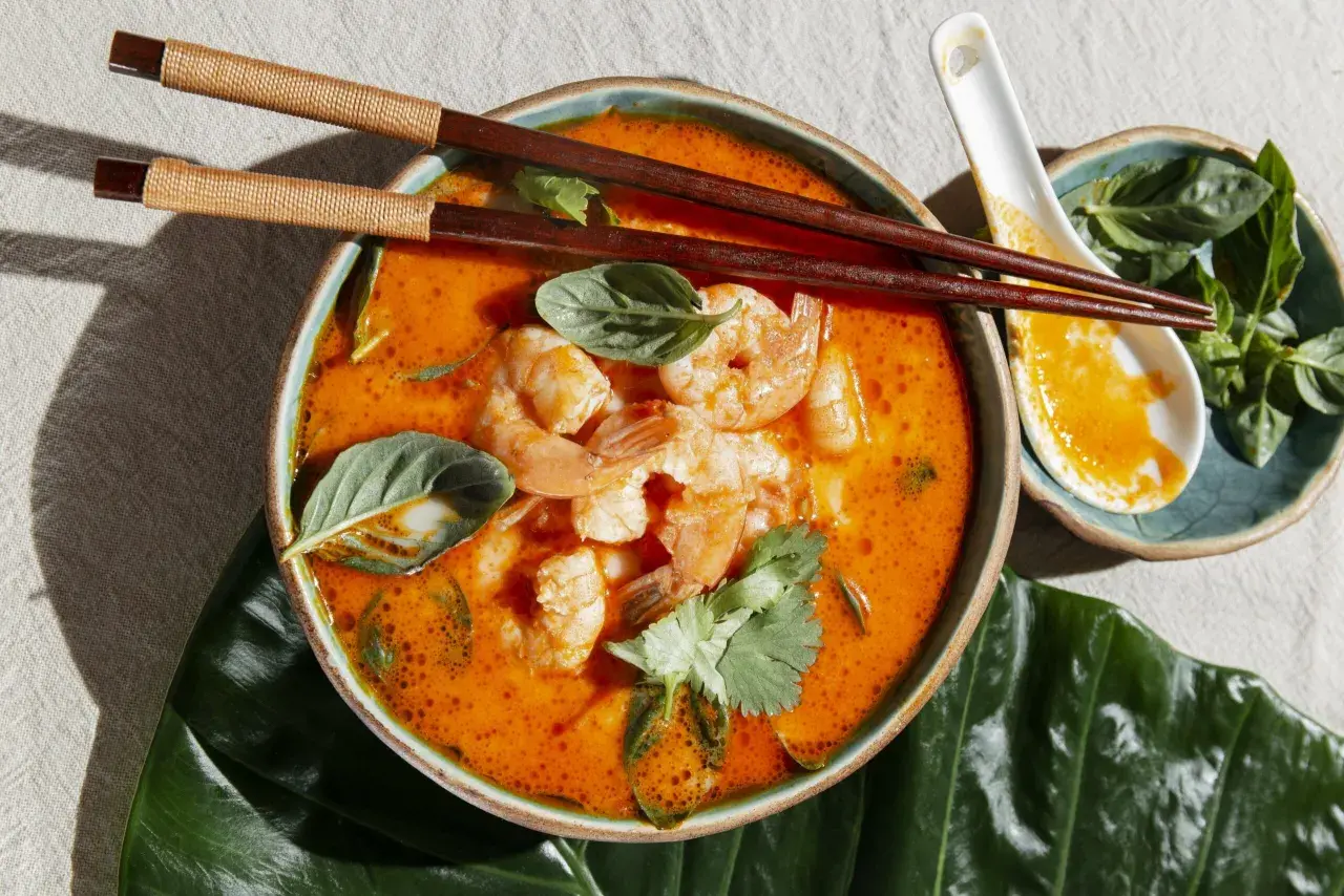 Aksamitny, pomarańczowy bulion z krewetkami i ziołami. Aromatyczny tom yam gotowy do spożycia pałeczkami.