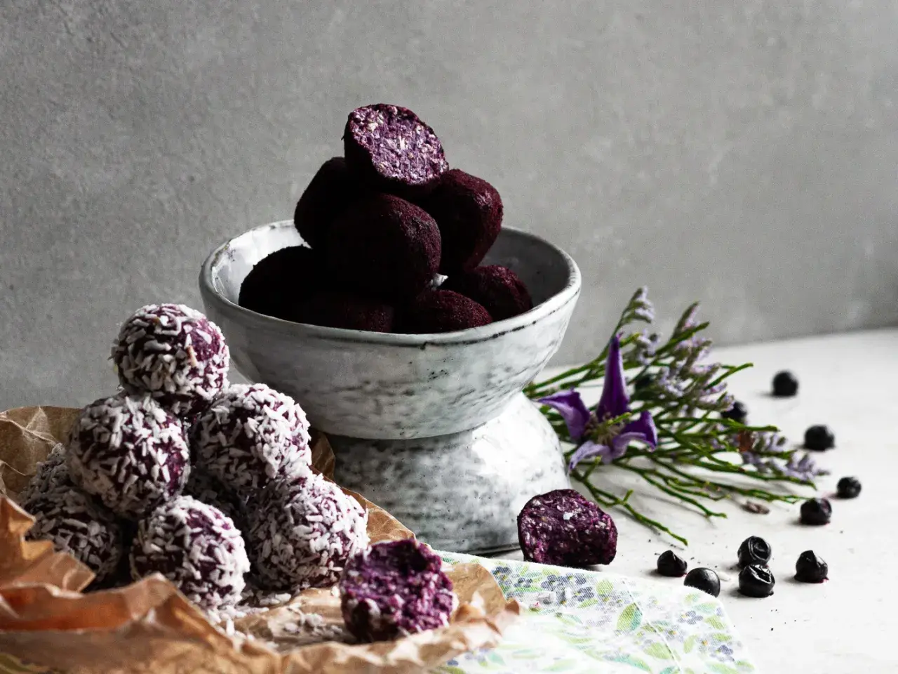 Läckra chokladbollar recept med blåbär och kokos. En skål med mörka bollar och en hög med kokosbollar.