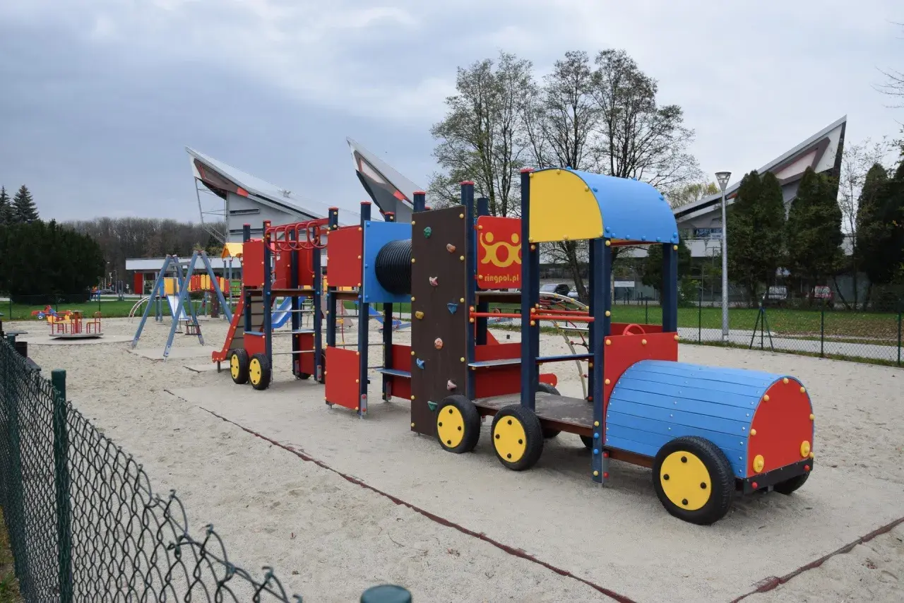 Kolorowy pociąg na placu zabaw w parku rozrywki Zawada. Dzieci mogą wspinać się, zjeżdżać i bawić się na tej interaktywnej konstrukcji.