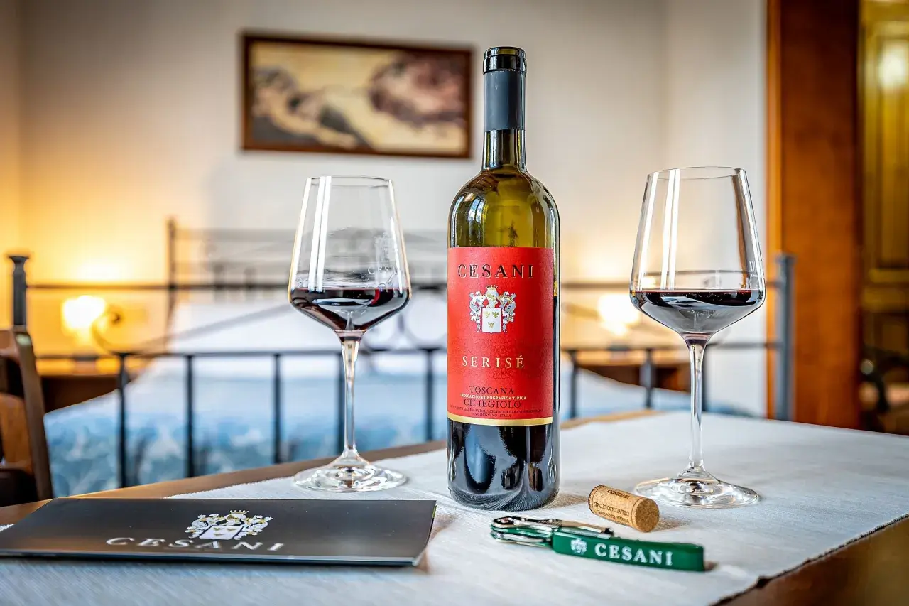 Un calice di vino rosso Cesani, una bottiglia di Serisé Ciliegiolo e un cavatappi, pronti per una degustazione alla Cesani winery.