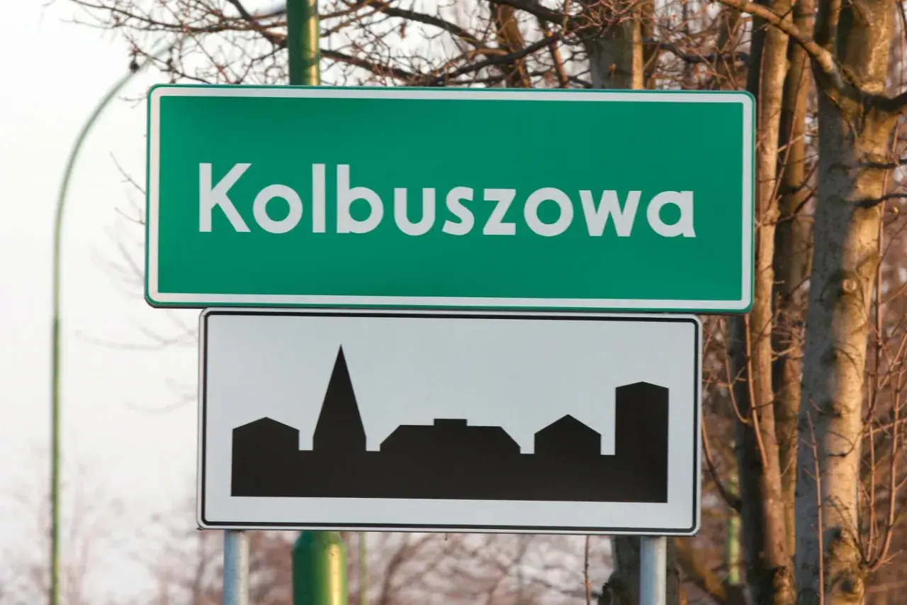 Znak drogowy Kolbuszowa z sylwetką zabudowy miejskiej. Wjazd do miasta.