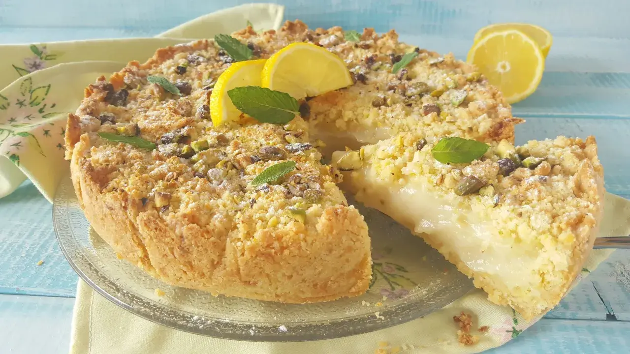 Deliziosa sbriciolata al limone con crema soffice, guarnita con pistacchi, menta e spicchi di limone fresco.