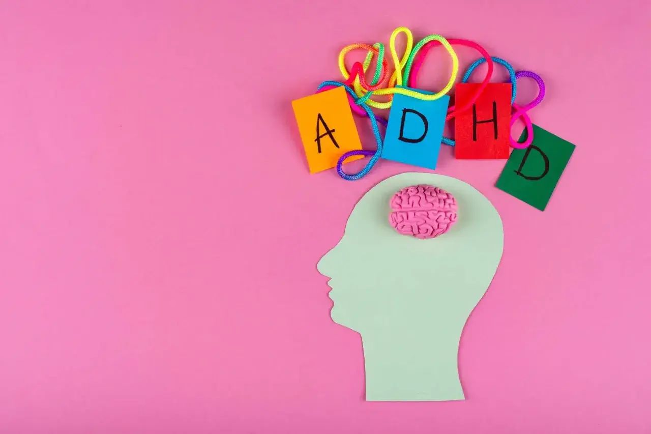 Sagoma di testa con cervello rosa e lettere colorate che formano ADHD, per capire come diagnosticarla.