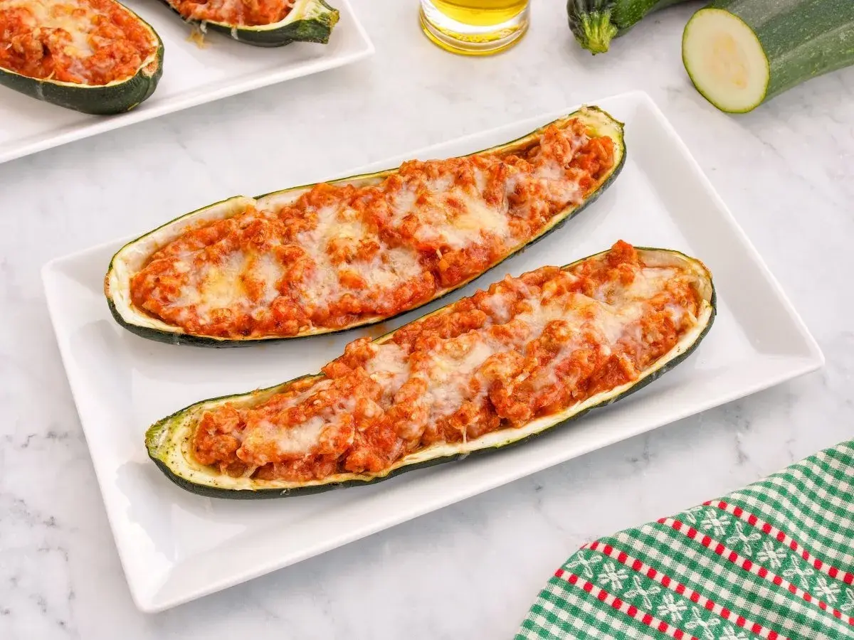 Dos calabacines rellenos de carne y queso gratinado, servidos en un plato blanco.