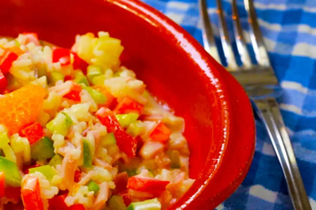 Omas Reissalat, ein bunter Mix aus Reis, Paprika, Sellerie und Mandarine, serviert in einer roten Schüssel.