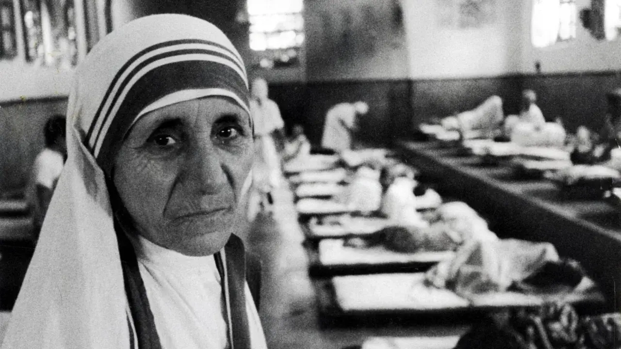 Mutter Teresa im Vordergrund, im Hintergrund Kranke in Betten. Die Aufnahme wirft Fragen auf, die zu Kritik an Mutter Teresa führten.