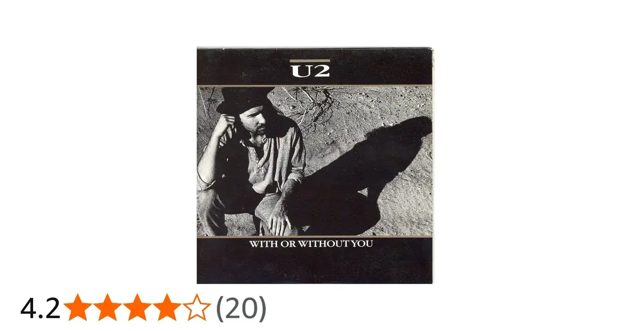 U2 w kadrze z piosenki "With or Without You". Mężczyzna w kapeluszu siedzi na ziemi, rzucając długi cień.