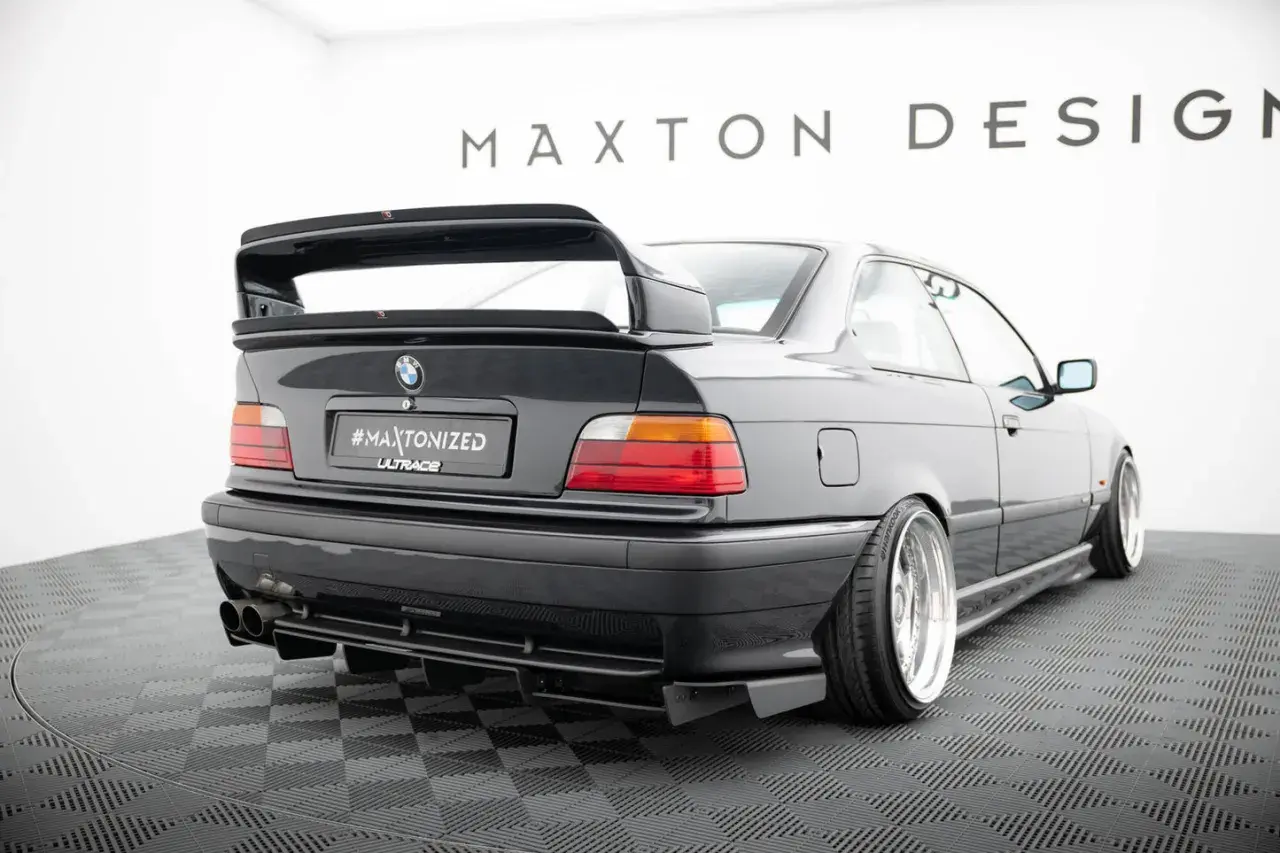 Czarne BMW E36 z tuningowym zderzakiem, dyfuzorem i dużym spoilerem.