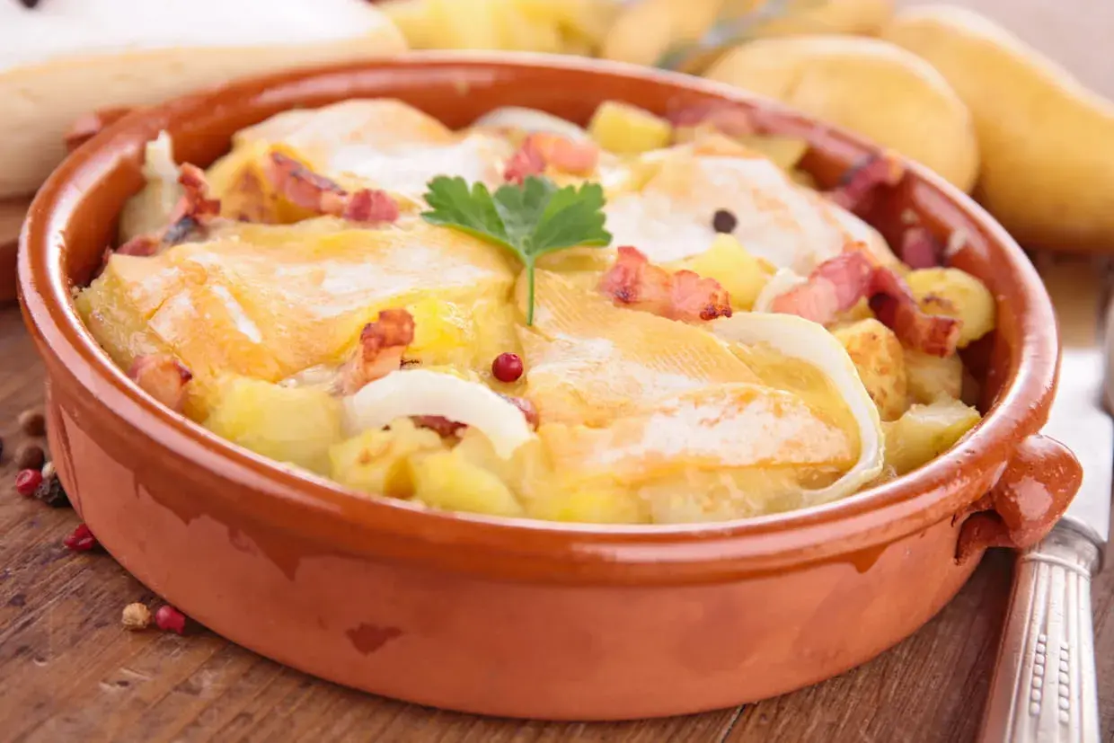 Plat gratiné avec pommes de terre, lardons et fromage à raclette fondant. Une recette réconfortante pour les soirées d'hiver.