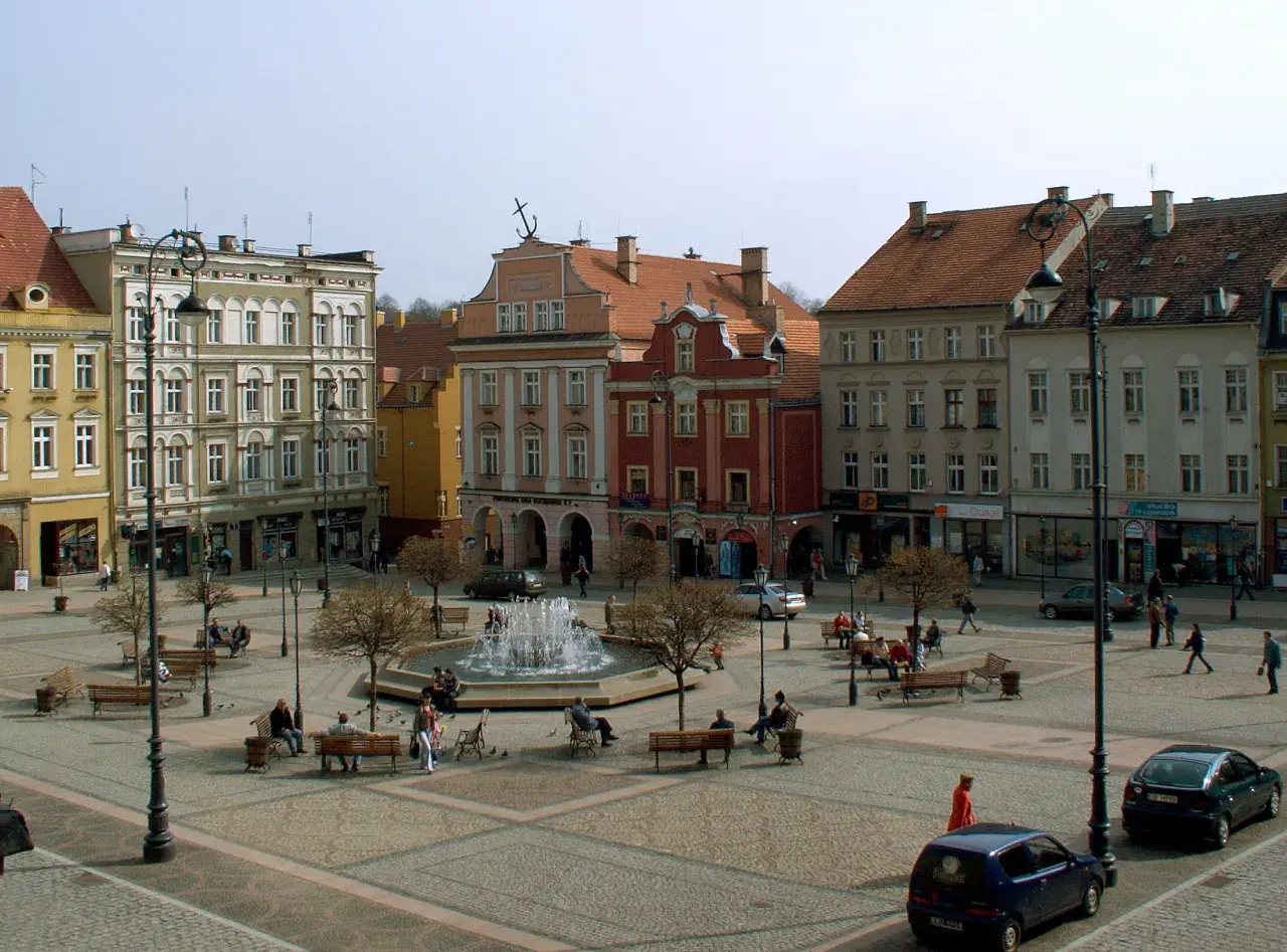 Rynek Wałbrzych tętni życiem. Ludzie odpoczywają przy fontannie, spacerują między kamienicami.