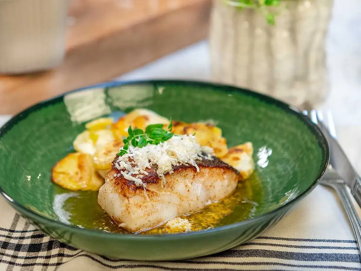 En lyxig torskrygg med krispiga potatisar, toppad med riven ost och färska örter. Ett perfekt lyxigt torskrygg recept för en fin middag.