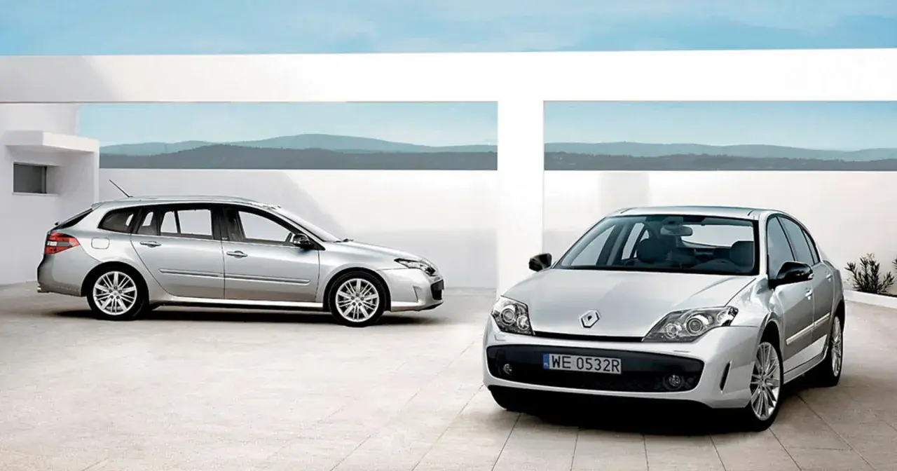 Dwa srebrne Renault Laguna 3 2.0 dCi: kombi i sedan, stojące na nowoczesnym placu z widokiem na góry.