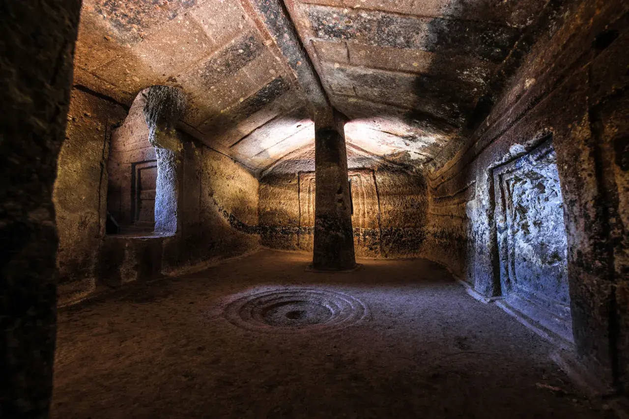 Interno di una domus de janas a Putifigari, con pilastro centrale e decorazioni scolpite.