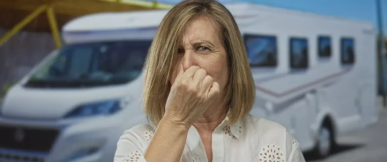 Frau hält sich die Nase wegen modrigem Geruch vor einem Wohnmobil.