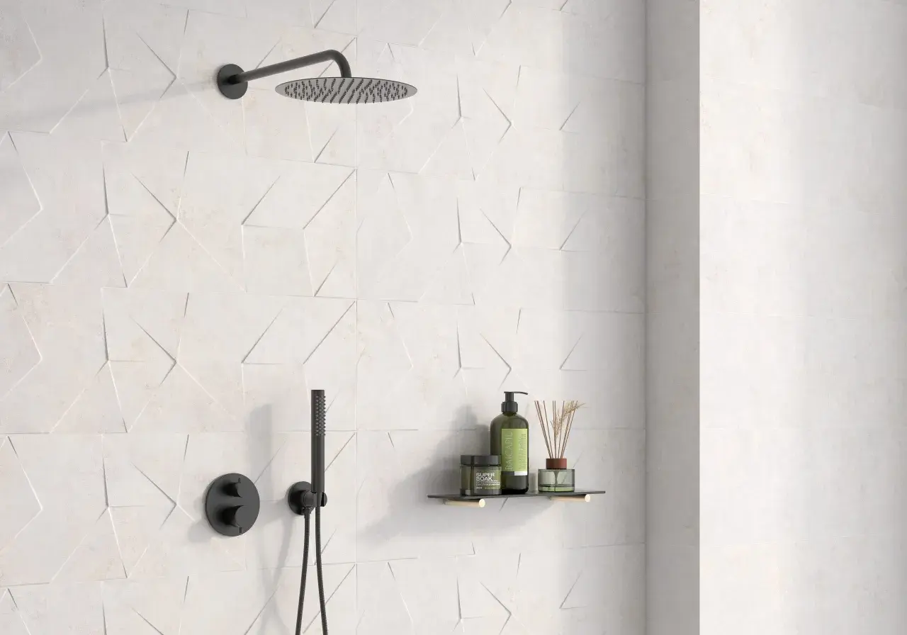 Ducha moderna con azulejo rectificado de diseño geométrico en blanco. Incluye rociador, grifería negra y estante con productos de baño.